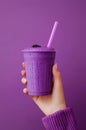 Female hand holding glass of blackberry milkshake on purple background. Royalty Free Stock Photo